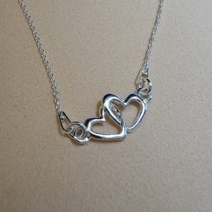 Colgante de plata de ley con dos corazones entrelazados y cadena plateada.